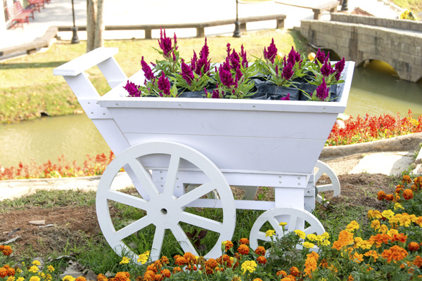 Whimsical container plantings, such as this flower cart, serve as the foundation for a traditional English cottage garden.